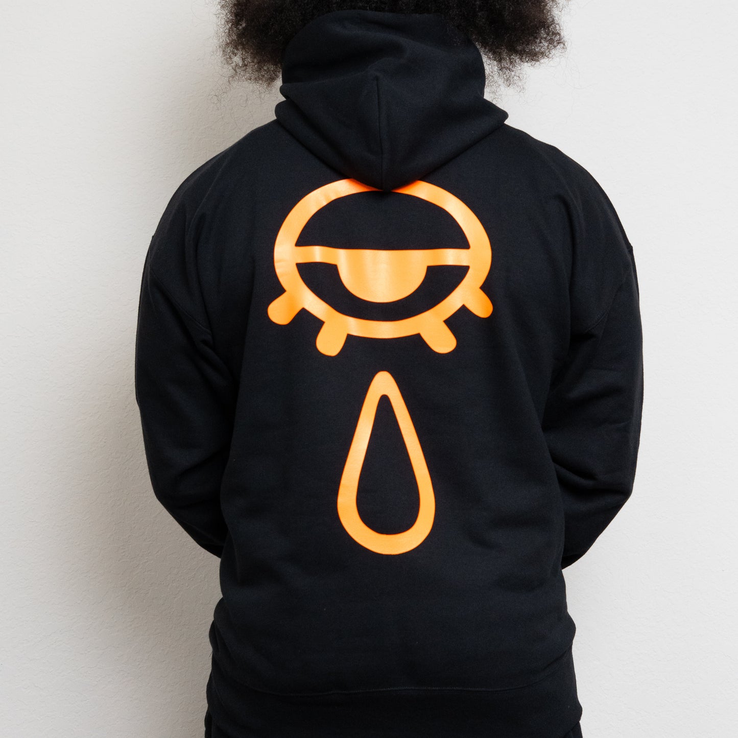back-side of a black hoodie with an eye and teardrop in the center