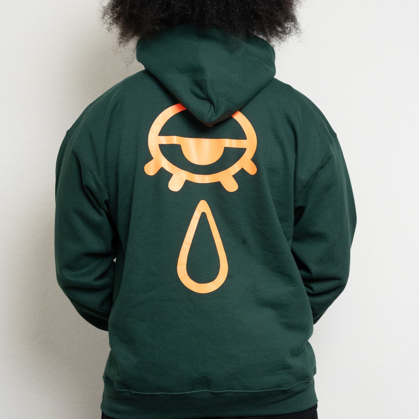 back-side of a deep forest green hoodie with an eye and teardrop in the center
