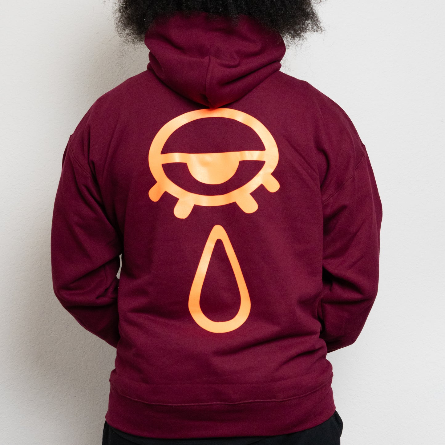 back-side of a maroon hoodie with an eye and teardrop in the center