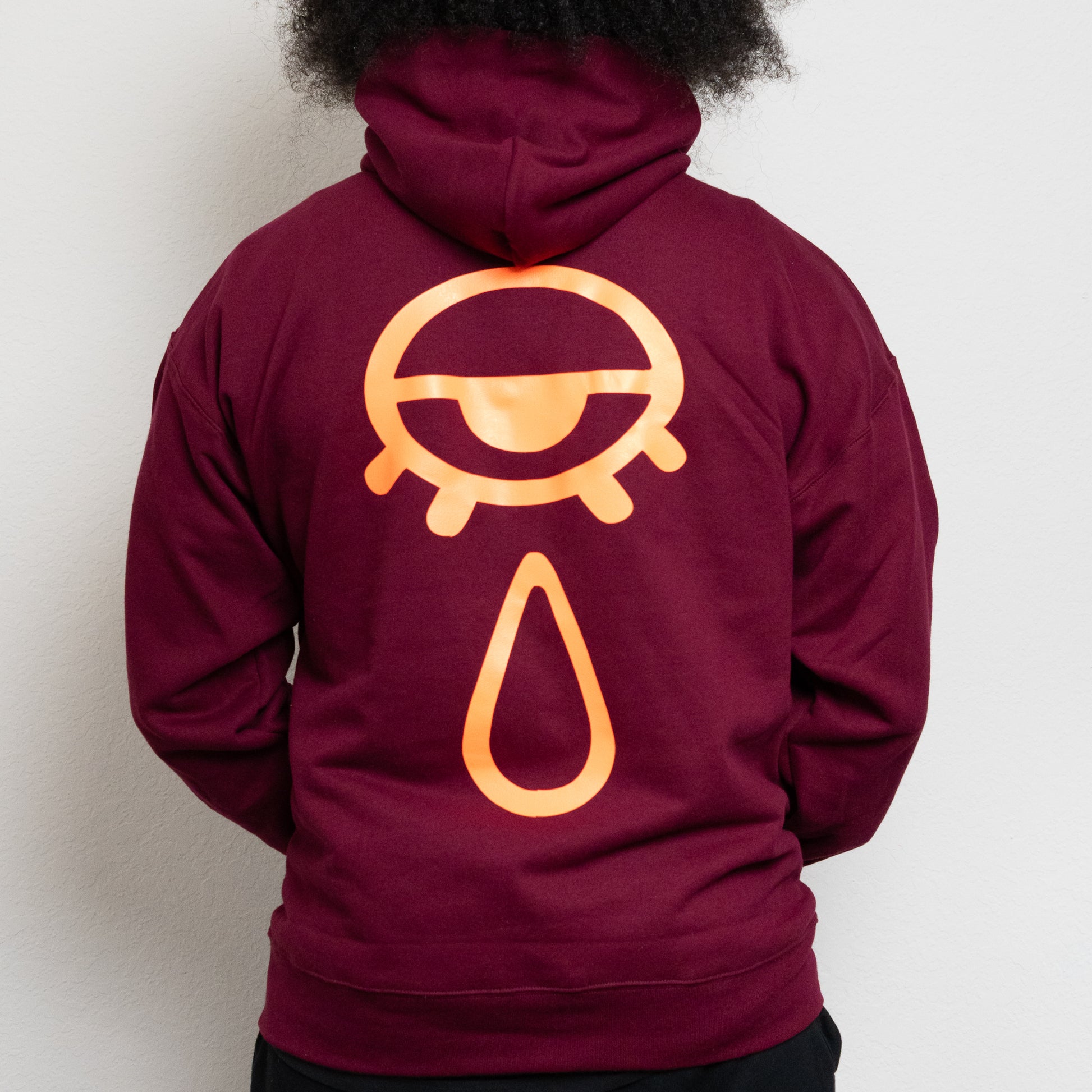 back-side of a maroon hoodie with an eye and teardrop in the center