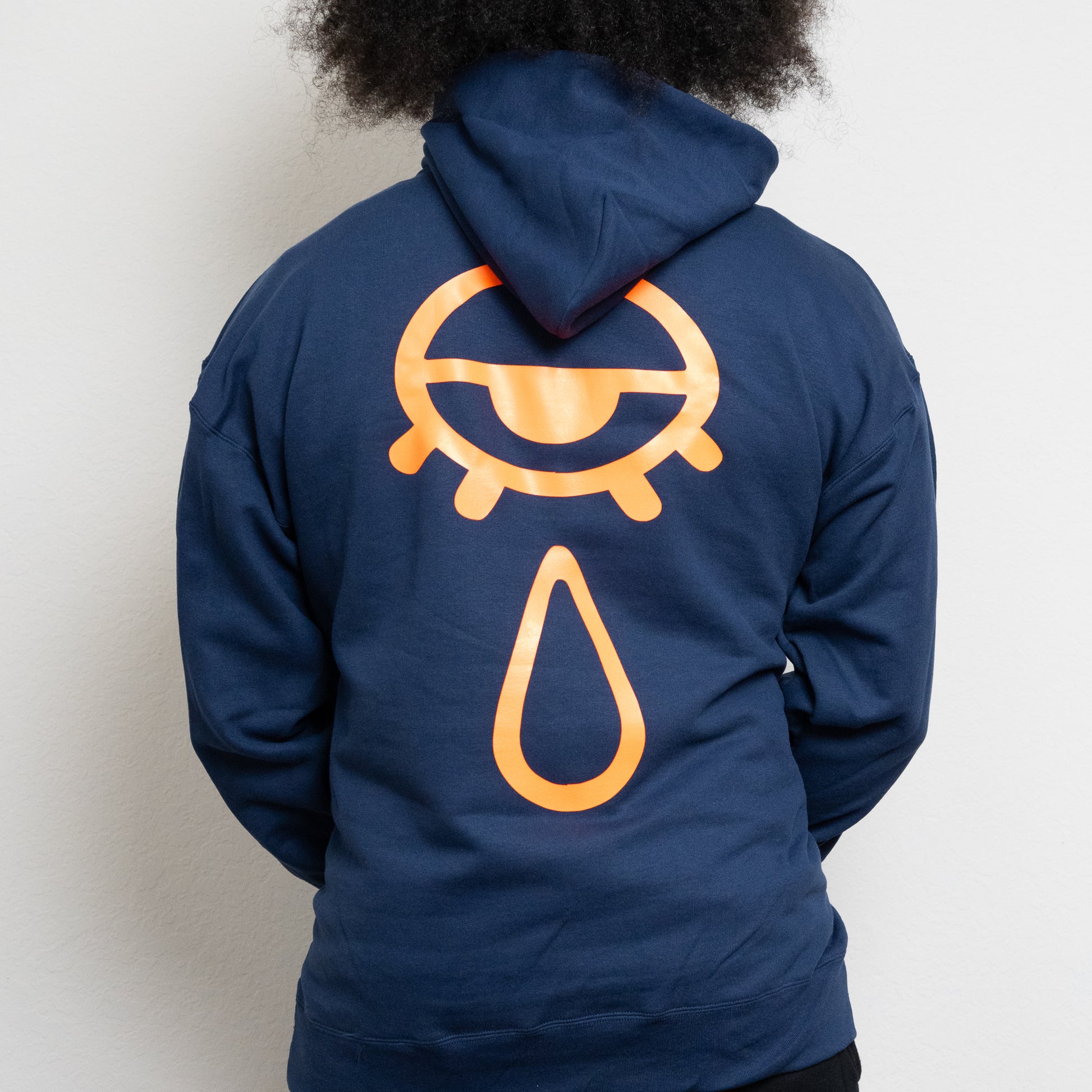 back-side of a navy hoodie with an eye and teardrop in the center
